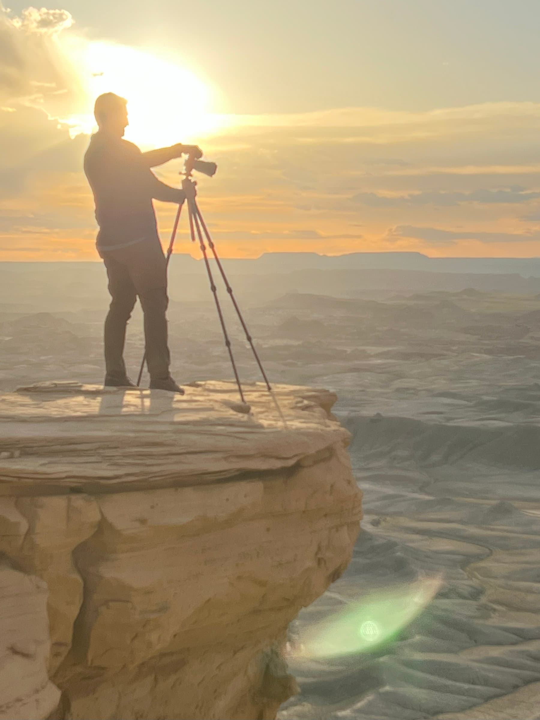Photographer silhouette near a high desert cliff at sunrise