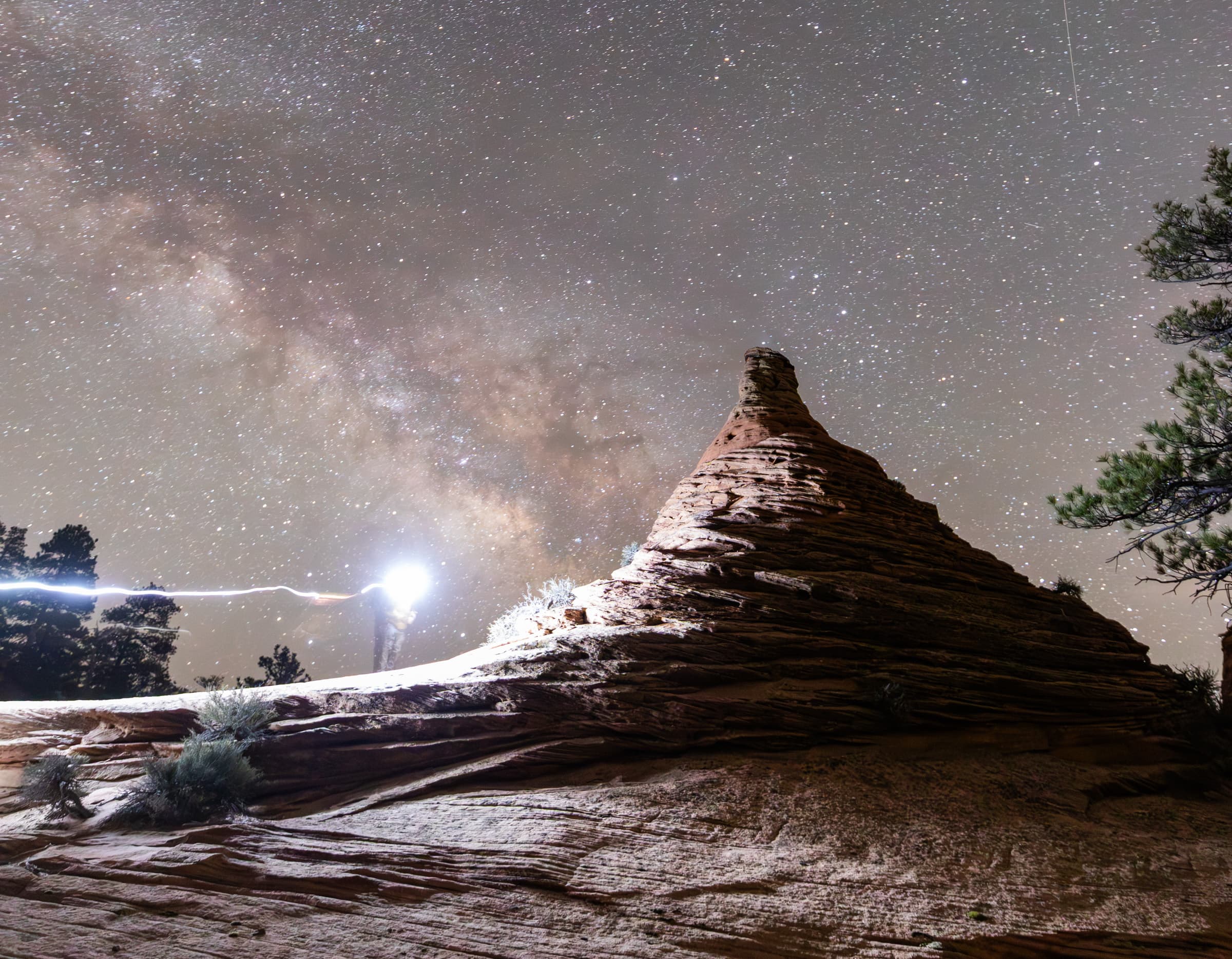 Milky Way over hoodoos with a photographer safely using white light in the foreground
